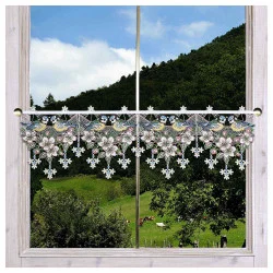 Ein Fenster mit einer dekorativen Plauener Spitze Scheibengardine, auf der bunte Vögel und Blumen abgebildet sind, bietet einen Blick auf eine grüne Landschaft mit Bäumen, Gras, Hügeln und grasenden Kühen unter einem teilweise bewölkten Himmel.