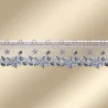 Eine Spitzenborte mit einem verschnörkelten blau-weißen Blumenmuster, das Blätter, Sternformen und ein detailliertes Geflecht entlang des Randes umfasst. Die Borte ist auf einem Hintergrund mit sanftem beigefarbenem Farbverlauf abgebildet.