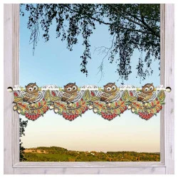 Gestickte Scheibengardine mit kleinen Eulen und bunten Blättern an einem hellen Holzfenster dekoriert.
Im Hintergrund sieht man einen blauen Himmel über grüner Landschaft