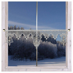 Ein Fenster mit weißen, kunstvollen Spitzengardine mit drei dekorativen Mustern, darunter Glocken, Kerzen und Schneeflocken, hängt an einer goldenen Stange. Draußen ist eine verschneite Landschaft mit einem Wald aus schneebedeckten Bäumen unter einem klaren, blauen Himmel zu sehen.