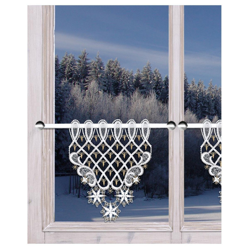 Ein kleines Fenster mit Holzrahmen, an dessen unterem Teil ein zarter weißer Spitzenvorhang hängt. Die Scheibengardine hat ein kompliziertes Netzmuster mit Ornamenten. Die schneebedeckte, frostige Szene draußen zeigt einen schneebedeckten Wald unter einem klaren Himmel.