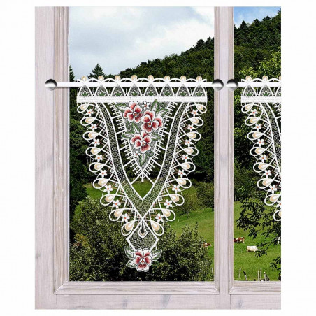 Ein Holzfenster zeigt einen Spitzenvolant mit floralen Mustern. Der Blick nach draußen zeigt eine üppig grüne Landschaft mit Bäumen und einigen grasenden Tieren auf einem Hügel. Ein Holzfenster zeigt einen Spitzenvolant mit floralen Mustern. Der Blick nach draußen zeigt eine üppig grüne Landschaft mit Bäumen und einigen grasenden Tieren auf einem Hügel.