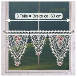 Ein Fenster mit einem dekorativen Spitzenvorhang mit floralen und geometrischen Mustern hängt an einer Stange.