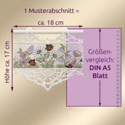 Eine dekorative Spitzenstickerei mit Blumen und Marienkäfern hängt an einer Stange. Die Maße sind angegeben: ca. 18 cm breit und 17 cm hoch. Ein vertikales Lineal und ein DIN A5-Blatt dienen zum Größenvergleich.