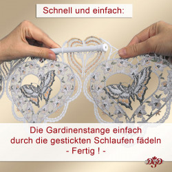 Zwei Hände fädeln eine weiße Gardinenstange durch genähte Schlaufen in einem dekorativen Spitzenbesatz mit Schmetterlings- und Herzmotiven. Ein deutscher Text erklärt, wie man die Gardine ganz einfach aufhängt.