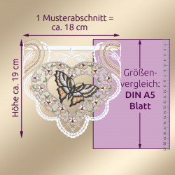 Spitzenstickerei als Scheibenhänger mit Schmetterling und Blumen in Herzform, ca. 19 cm hoch und 18 cm breit. Abgebildet ist ein Größenvergleich mit einem DIN A5-Blatt und einem Lineal. Der Text erklärt die Maße.