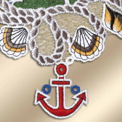 Eine Nahaufnahme der bestickten Vogtländischen Spitze mit Muscheln und einem roten Anker mit blauen Akzenten, alles auf einem gold-beigen Hintergrund gestickt – perfekt als maritime Bad-Deko oder Fensterbilder.