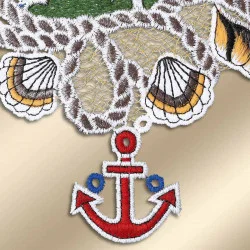 Eine Nahaufnahme der bestickten Vogtländischen Spitze mit Muscheln und einem roten Anker mit blauen Akzenten, alles auf einem gold-beigen Hintergrund gestickt – perfekt als maritime Bad-Deko oder Fensterbilder.