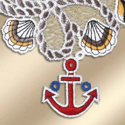 Eine Nahaufnahme der bestickten Vogtländischen Spitze mit Muscheln und einem roten Anker mit blauen Akzenten, alles auf einem gold-beigen Hintergrund gestickt – perfekt als maritime Bad-Deko oder Fensterbilder.