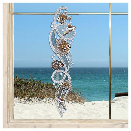 Ein dekoratives Spitzen-Fensterbild mit vogtländischer Spitze mit Fischen, Muscheln und Meeresmotiven hängt in einem Fenster mit Blick auf einen Sandstrand, Meereswellen und einen klaren blauen Himmel. Ein dekoratives Spitzen-Fensterbild mit vogtländischer Spitze mit Fischen, Muscheln und Meeresmotiven hängt in einem Fenster mit Blick auf einen Sandstrand, Meereswellen und einen klaren blauen Himmel.