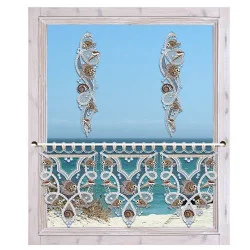 Ein weiß umrahmtes Fenster mit kunstvollen Spitzendekorationen der Vogtländischen Spitze, mit zwei vertikalen Girlanden oben und einem komplizierten Spitzenvolant unten. Draußen bilden das ruhige blaue Meer und der klare Himmel ein wunderschönes Fensterbild.