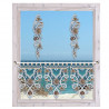 Ein weiß umrahmtes Fenster mit kunstvollen Spitzendekorationen der Vogtländischen Spitze, mit zwei vertikalen Girlanden oben und einem komplizierten Spitzenvolant unten. Draußen bilden das ruhige blaue Meer und der klare Himmel ein wunderschönes Fensterbild.