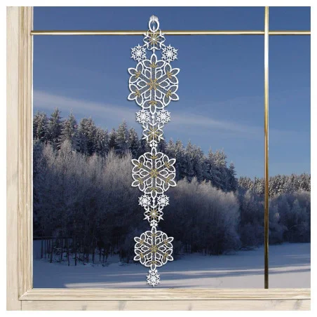 Eine dekorative Giralnde aus gestickten weißen Schneeflocken hängt in einem Fenster, aus dem ein verschneiter Wald und ein blauer Himmel zu sehen sind.