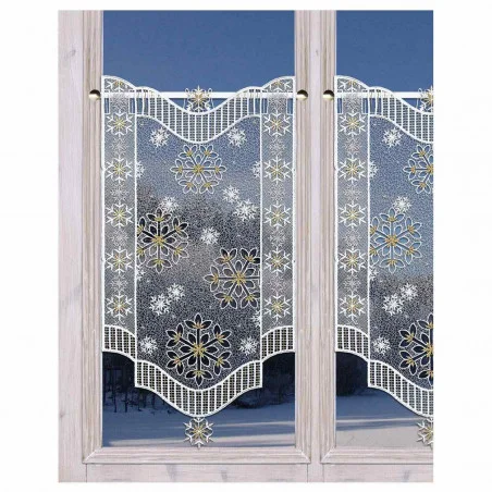 Ein weißer Spitzenvorhang mit goldenen und weißen Schneeflockenmustern hängt an einer Stange über einem Fenster. Der Fensterrahmen ist aus hellem Holz, und im Hintergrund ist eine verschneite Szene im Freien zu sehen.