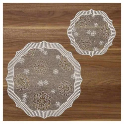 Zwei runde, dekorative Spitzendeckchen mit weißen Schneeflockenmustern und einem Wellenrand liegen auf einer Holzoberfläche mit naturbrauner Maserung.