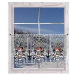 Ein Spitzenvorhang mit Schneemann- und Vogelmotiven hängt an einem Holzfenster, durch das eine verschneite Landschaft mit Bäumen und einem klaren blauen Himmel zu sehen ist.