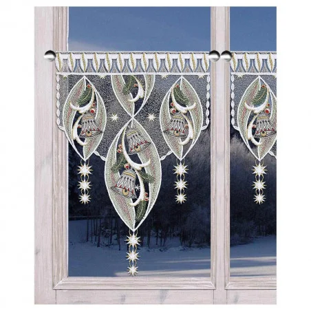 Spitzenvorhänge mit verschlungenen Glocken- und Sternmustern hängen an einem Fenster, aus dem eine verschneite Winterlandschaft zu sehen ist.