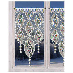 Dekorative Spitzenvorhänge mit verschlungenen Glocken und Tannenzweigen hängen an einem Fenster und geben den Blick auf eine verschneite Winterlandschaft und dunkle Bäume frei.