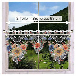 Ein dekorativer Spitzenvorhang mit bunten Blumenmustern hängt an einem Fenster. Eine Messlinie mit Pfeilen zeigt die Breite von etwa 63 cm an. Außerhalb des Fensters sind grüne Hügel und Bäume zu sehen.