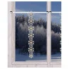 Eine frostige Winterszene vor einem Fenster mit schneebedeckten Bäumen; eine dekorative vertikale Girlande mit Schneeflockenornamenten hängt von einer Gardinenstange über dem Fenster.
