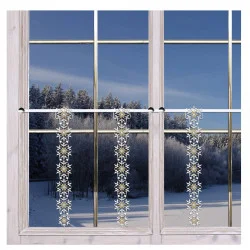 Eine verschneite Landschaft mit Bäumen ist durch ein Fenster zu sehen. Drei vertikale Scheibengardinen mit dekorativen weißen und goldenen Schneeflocken hängen vom Fensterrahmen herab.