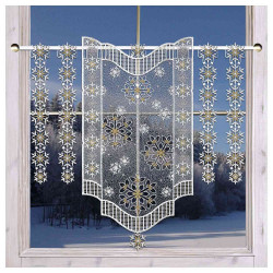 Ein Fenster mit durchsichtigen Spitzenvorhängen mit verschlungenen Schneeflockenmustern; draußen sind verschneite Bäume und ein klarer blauer Winterhimmel zu sehen.