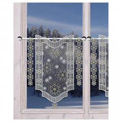 Ein Fenster mit gesticken weißen Vorhängen aus Schneeflocken und Sternenmustern, wobei draußen ein verschneiter Wald zu sehen ist. Die Vorhänge sind an einer Stange aufgehängt und haben an den Rändern dekorative Ausschnitte.