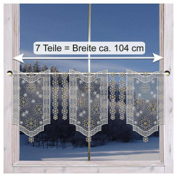 Spitzenvorhänge mit Schneeflocken hängen an einem Fenster und geben den Blick auf eine verschneite Landschaft frei.