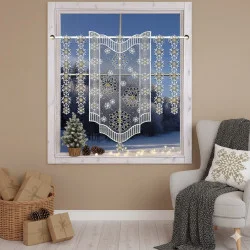 Spitzenvorhänge mit Schneeflocken hängen an einem Fenster und geben den Blick auf eine verschneite Landschaft frei.
