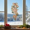 Ein festlich gesticktes Ornament in Plauener Spitze mit Sternen, einem Herz, Grünzeug und einer Schleife hängt als Fensterbild Lebkuchen im Fenster. Draußen ist eine Schneelandschaft zu sehen, auf einem Tisch stehen Kerzen, Tannenzweige und getrocknete Orangenscheiben.