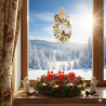 Ein festliches Fenster mit Blick auf einen verschneiten Wald bei Sonnenaufgang. Auf der Fensterbank steht ein Adventskranz mit drei roten Kerzen, umgeben von Grünzeug und Beeren, zwei Engelsfiguren und einem Plauener Spitze Fensterbild, das die Fensterscheibe schmückt.