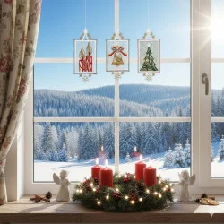 Durch ein mit festlichen Fensterbildern Adventszeit und Kreuzstich-Ornamenten geschmücktes Fenster blickt man in einen verschneiten Wald. Auf der Fensterbank steht ein Kerzenkranz mit vier roten Kerzen, zwei Engelsfiguren, Tannenzapfen und einer warmen Lichterkette.
