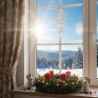 Eine sonnenbeschienene Schneelandschaft ist durch ein Fenster zu sehen, das mit einem Plauener Spitze Fensterbild Schneeflocke geschmückt ist. Auf der Fensterbank sorgt ein Weihnachtskranz mit vier roten Kerzen, Lichterketten und zwei Engelsfiguren für gemütliches Winterflair.