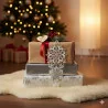 Drei eingepackte Weihnachtsgeschenke liegen auf einem flauschigen Teppich neben einem leuchtenden Weihnachtsbaum, der mit Winterflair und Plauener Spitze geschmückt ist. Ein "Für Dich"-Anhänger krönt die gemütliche, festliche Szene, die perfekt für die Weihnachtszeit ist.