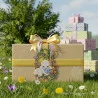Verschönern Sie Ihre Frühlingsdekoration mit dieser bezaubernden hellbraunen Geschenkbox, die mit einem gelben Band verziert ist und das "Fensterbild Schäfchen & Blaumeisen" (Vogtländische Spitze, weiß & bunt, 31x21 cm) zeigt. Eingebettet in Wildblumen, zwischen pastellfarbenen Geschenken, ist