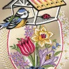 Das Fensterbild Frühlingsgezwitscher Plauener Spitze zeigt einen gestickten Vogel auf einem Futterhäuschen, in dessen Nähe ein roter Marienkäfer sitzt. Darunter befinden sich gestickte Darstellungen einer gelben Narzisse, einer rosa Tulpe und eines violetten Krokus zwischen grünen Blättern