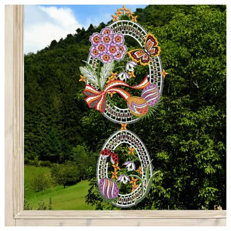 Zwei ovale Spitzenornamente mit der Aufschrift "Fensterbild Ostertraum Vogtländischer Spitze lila" (40x18 cm) sind in einem Fenster hängend ausgestellt. Sie zeigen violette Blumenstickereien und einen Schmetterling.
