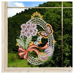 Das "Fensterbild Osterei mit Schmetterling Plauener Spitze helllila" ist eine eiförmige Fensterdekoration aus Spitze mit aufgestickten lila Blumen, einem gelb-orangen Schmetterling, einem roten Band und Ostereiern. Draußen sind grüne Bäume und ein blauer Himmel mit Wolken zu sehen.