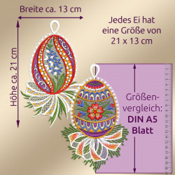 Abgebildet sind zwei aufwändig gestickte Ostereier mit bunten Blumenmustern. Die Eier sind etwa 21 cm hoch und 13 cm breit. Ein metrisches Lineal und ein A5-Blatt veranschaulichen ihre Größe. Der deutsche Text liefert Maße und Vergleiche.