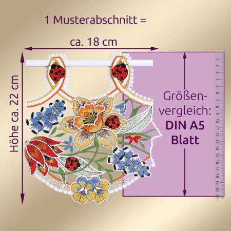 Ein besticktes Spitzenstück mit floralen Motiven in Gelb, Blau und Rot, darunter Marienkäfer und Lilien. Das Stück hat eine Höhe von ca. 22 cm und eine Breite von ca. 18 cm und ist neben einem lila DIN A5-Blatt ausgestellt. Der deutsche Text gibt die Maße an.
