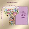 Eine gestickte Dekoration zeigt ein braunes Häschen, das ein verziertes Ei hält, umgeben von Blumen und Bändern. Lila Pfeile und Text geben die Maße von 23 cm in der Höhe und 18 cm in der Breite an, die neben einem DIN-A5-Blatt auf lila Hintergrund gezeigt werden, um den Maßstab zu bestimmen.