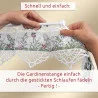Zwei Hände fädeln einen weißen Spitzenvorhang mit gestickten Blumenmustern auf eine weiße Stange. Der Hintergrund ist hellbeige. Über und unter dem Bild erscheint ein deutscher Text, der die Montage der Gardine als einfach und schnell beschreibt.
