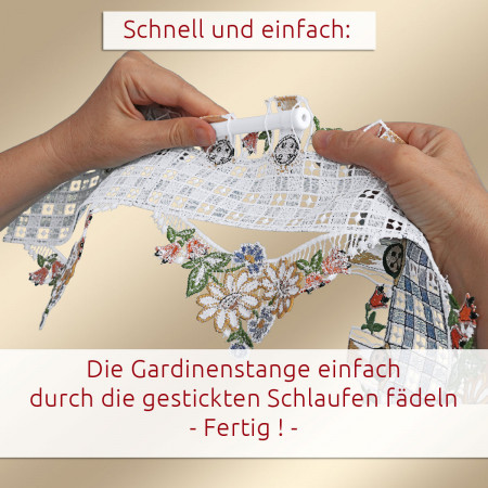 Zwei Hände fädeln einen weißen Stab durch die genähten Schlaufen am oberen Ende eines dekorativen Spitzenvorhangs mit floralem Muster. Der Hintergrund ist einfarbig. Ein deutscher Anleitungstext zeigt, wie man die Stange durch die Schlaufen führt, um die Gardine aufzuhängen.