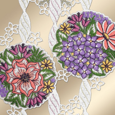 Zwei runde Spitzenaufnäher zeigen detaillierte Blumenstickereien. Ein Aufnäher zeigt rosa, gelbe und lila Blüten mit grünen Blättern, der andere lila, gelbe und orangefarbene Blumen. Weiße Spitze mit Blumenmotiven verbindet die Kreise auf einem beigen Hintergrund.