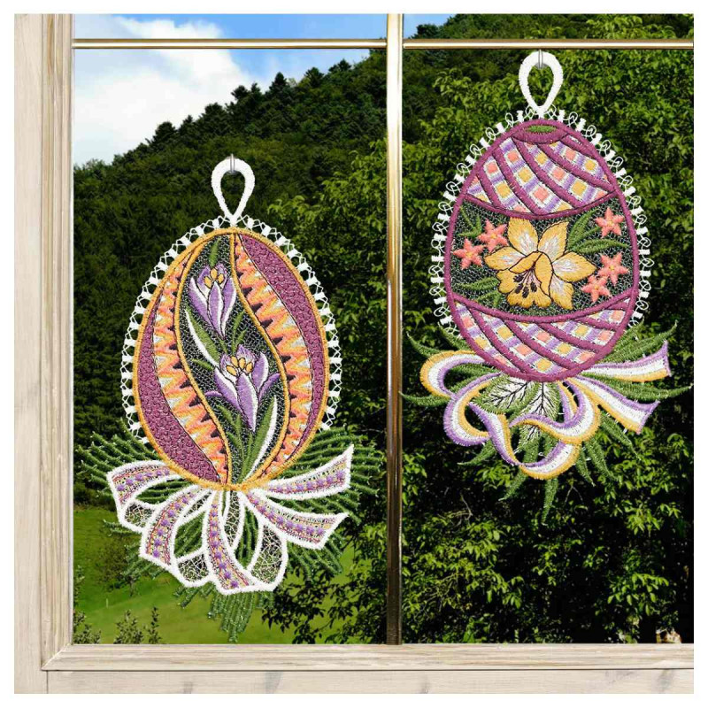 Das Fensterbilder 2er Set Ostereier mit Krokus und Narzisse Plauener Spitze lila besteht aus zwei eiförmigen Fensterornamenten, eines mit violetten Krokussen und dekorativen Mustern, das andere mit gelben Blumen vor einem Hintergrund aus grünen Bäumen und Hügeln.
