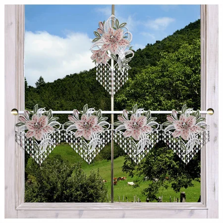 Ein helles holzgerahmtes Fenster ist mit durchsichtigen Spitzenvorhängen mit rosa und grünen Blumenmustern und geometrischen Formen bedeckt. Durch das Fenster sind grüne Hügel, vereinzelte Bäume und grasende Kühe unter einem teilweise bewölkten Himmel zu sehen.