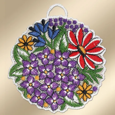 Ein kreisförmig gestickter Aufnäher zeigt große rote, blaue und gelbe Blüten sowie zahlreiche kleine lila Blüten mit gelben Zentren. Grüne Blätter umgeben die Blüten. Der Aufnäher ist mit einem gezackten weißen Rand eingefasst und hat oben eine kleine Schlaufe zum Aufhängen.