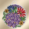 Ein kreisförmig gestickter Aufnäher zeigt große rote, blaue und gelbe Blüten sowie zahlreiche kleine lila Blüten mit gelben Zentren. Grüne Blätter umgeben die Blüten. Der Aufnäher ist mit einem gezackten weißen Rand eingefasst und hat oben eine kleine Schlaufe zum Aufhängen.