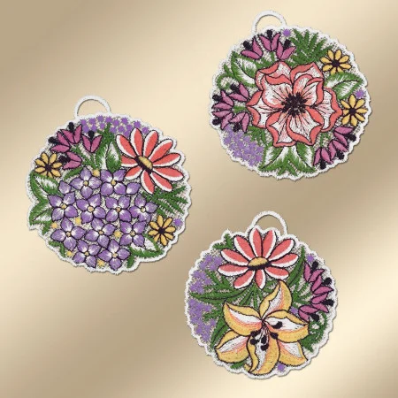 Drei kreisförmig gestickte Ornamente mit weißen Rändern sind auf einem beigen Hintergrund angeordnet. Das linke Ornament zeigt violette und rote Blumen, das obere rechts zeigt rosa und violette Blumen und das untere rechts zeigt gelbe, violette und orange Blumen.