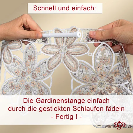 Zwei Hände halten eine weiße Gardinenstange, die durch gestickte Schlaufen einer Spitzen-Gardine mit Blumenmuster geführt wird. Im Bild ist ein deutscher Text eingeblendet: "Schnell und einfach: Die Gardinenstange einfach durch die gestickten Schlaufen fädeln - Fertig!".